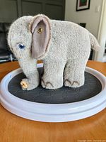 Right side view of grey Steiff plush elephant showing ear button and blue eye