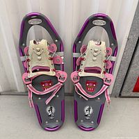 Full view of both snowshoes showing color, model badge, bindings, overall wear