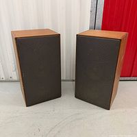 Front view of both ADS L810 speakers showing cherry veneer cabinets and grilles