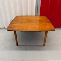 Full view of square wood coffee table with four round legs