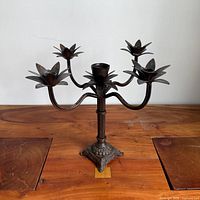 Full front view of 5-arm wrought iron candelabra on wood surface