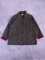 Front view of olive faux suede jacket with red cuffs and button closure
