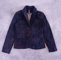 Full front view of blue suede blazer lying flat showing overall design, pockets and button closure