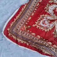 Corner of red paisley scarf showing hem and pattern