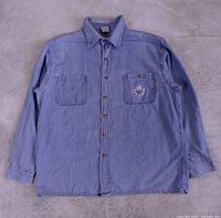 Full front view of denim shirt showing overall style, buttons, pockets, logo placement