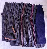 Row of 23 folded leather and suede pants with shoes placed at side