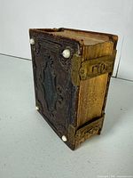 Front view showing embossed leather cover, brass clasp and studs