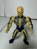 Front view of glow-in-the-dark Scare Glow figure showing skeleton paint and purple accessories
