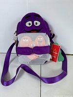 Front view Grimace plush bag with second bag wrapped in tissue, tags visible