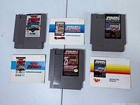 Three NES Jeopardy cartridges and three instruction booklets laid out