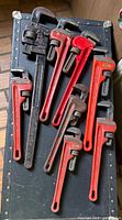 All eight pipe wrenches laid out on trunk