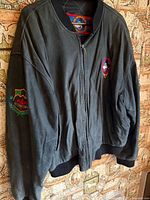 Full view of front of jacket showing zipper, chest patch, sleeve patch, knit trim