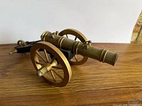 Side view of brass barrel cannon on wooden wheels