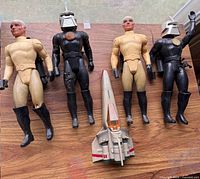 Group shot of two beige human figures, two black Cylons and Colonial Viper