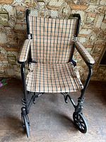 Front view of folding transport wheelchair with plaid fabric seat and back