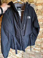 Front view of black North Face parka on hanger