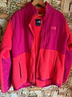 Front view of two-tone pink North Face fleece jacket, unzipped