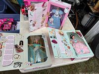Three open book-style Barbie boxes showing dolls and interior artwork