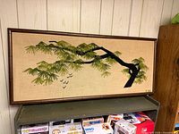 full view of rectangular yarn art in bamboo frame showing branch, foliage and birds