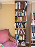 Full view of tall wood veneer bookcase filled with books