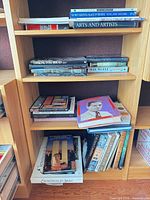 Four shelves filled with assorted hardcover books, visible titles on arts, architecture and space