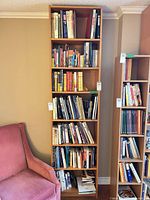 Tall narrow bookcase with seven filled shelves of assorted books