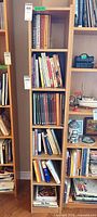 Tall narrow bookcase with six shelves packed with cookbooks