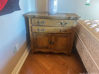 Front angled view of wood cabinet next to bed