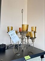 Full view of metal hanging candle chandelier with six amber glass votive cups, tag visible