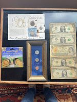 Overview of all coins, souvenir tokens, framed display, and five banknotes mounted on cardboard