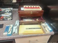 Overview of wood chest, Gero Zilduro box, souvenir spoons on counter