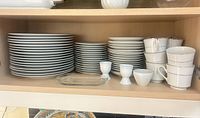 Shelf with stacked dinner plates, salad plates, saucers, cups, egg cups, butter dish