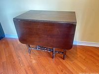 Gateleg table closed against wall showing dark wood finish and turned legs