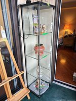 Full front view of glass display cabinet showing three shelves and interior light fixture