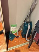 Corner view showing canister vacuum, hose, wand, floor head, crevice tool and bag package