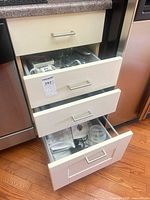 Three kitchen drawers open showing assortment of utensils