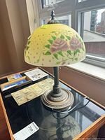 Full view of lamp on table showing painted shade and metal base