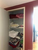 Full view of closet with four shelves of assorted linens