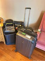 Full view of lot showing Heys suitcase front, black suitcase behind, backpack and other bags in blue bin