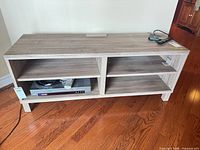 Front view of laminate media stand showing four shelf compartments