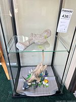 Full view of pottery bust on upper shelf and wood cat with textile on lower shelf