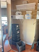 Stacked Rubbermaid totes, black milk crate and assorted clear bins on shelves