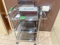 Full view of chrome rolling cart with tissue box covers on top