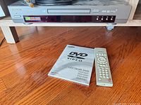 Front view of Samsung DVD-S221 player with remote and manual