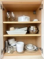 Cabinet with three shelves of serving ware, bakeware, bowls, goblets, salt and pepper shakers