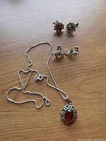 All items: necklace with amber pendant, two pairs screw-back earrings