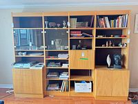 Full frontal view of the three-section wall unit with shelves, glass doors and lower cabinets