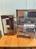 Sealed boxes of allen + roth pendant and flush mounts on table