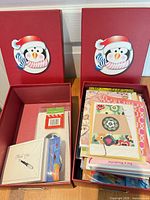 Two red penguin boxes open showing assorted cards and envelopes