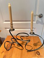 front view of black wrought iron two-arm candelabra with two candles inserted